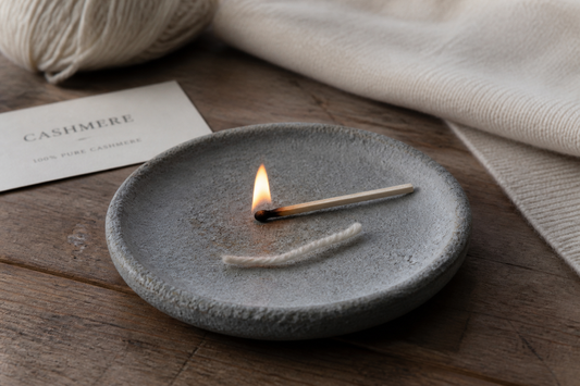 A cashmere thread beside a match on a heatproof stone dish